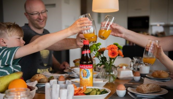 Familie am Frühstückstisch trinkt Rotbäckchen Morgenstark