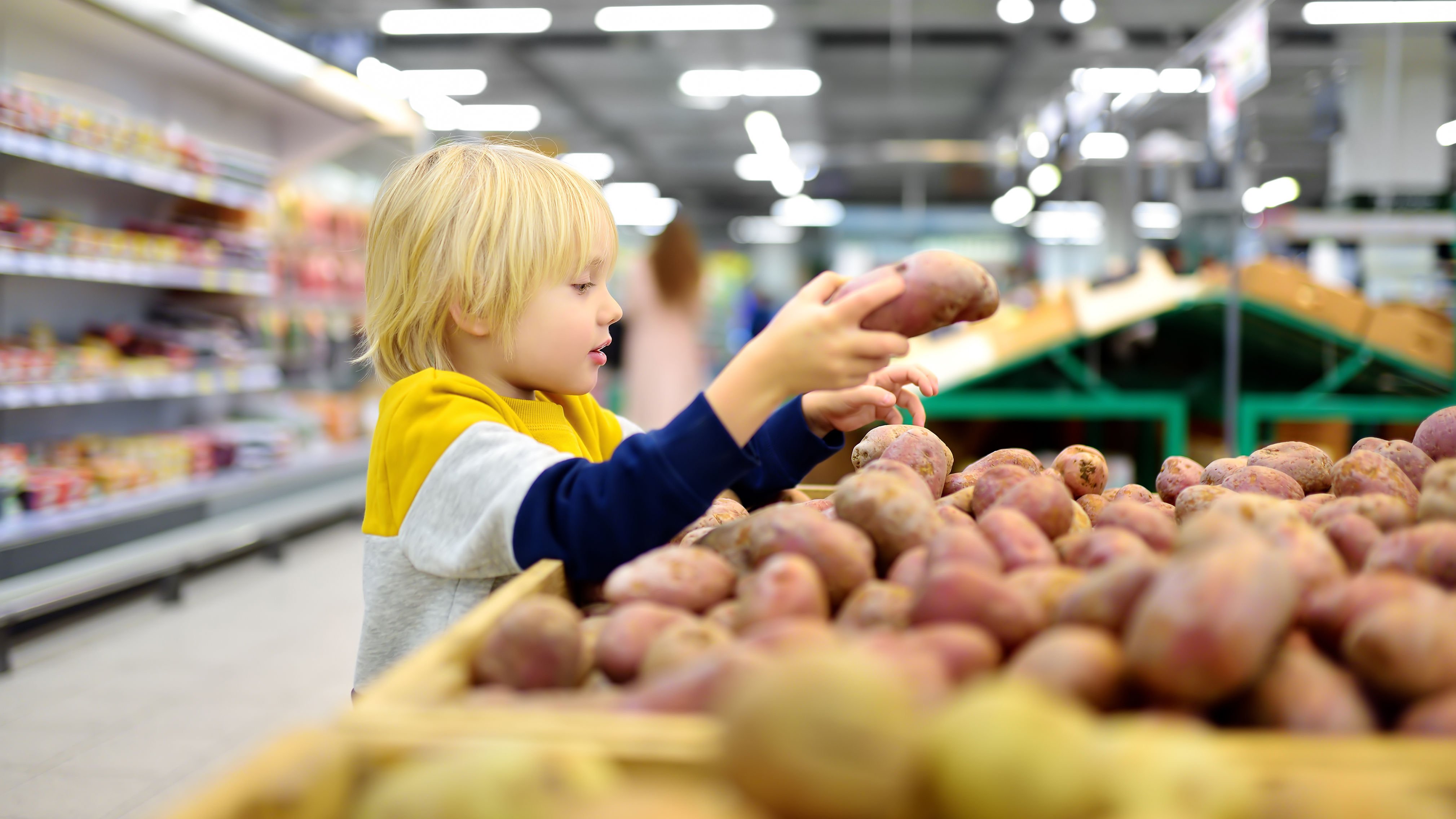 Kind betrachtet Kartoffeln in Supermarkt